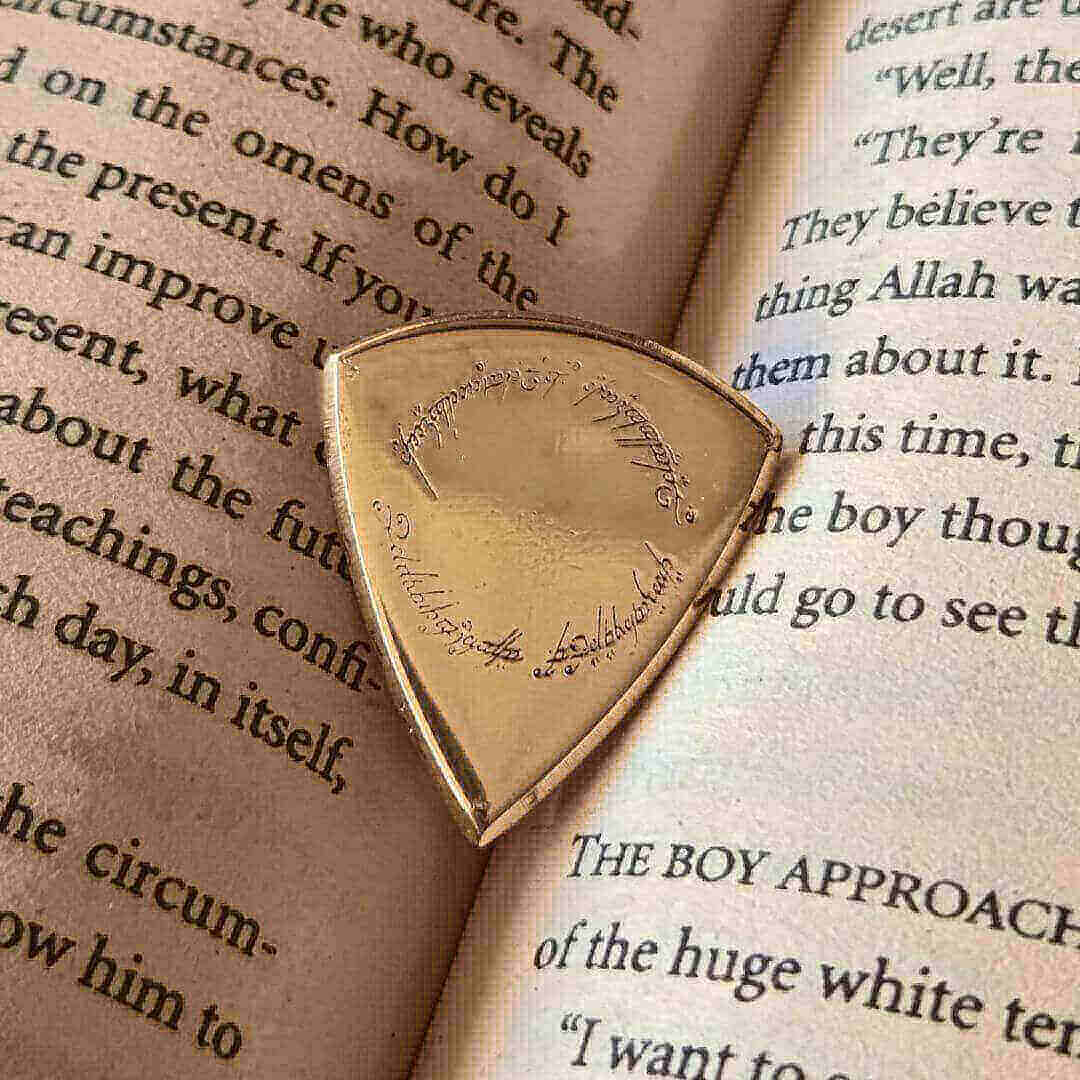 Close-up macro detail of the polished, smooth surface and beveled edge of the Knc Picks brass pick.