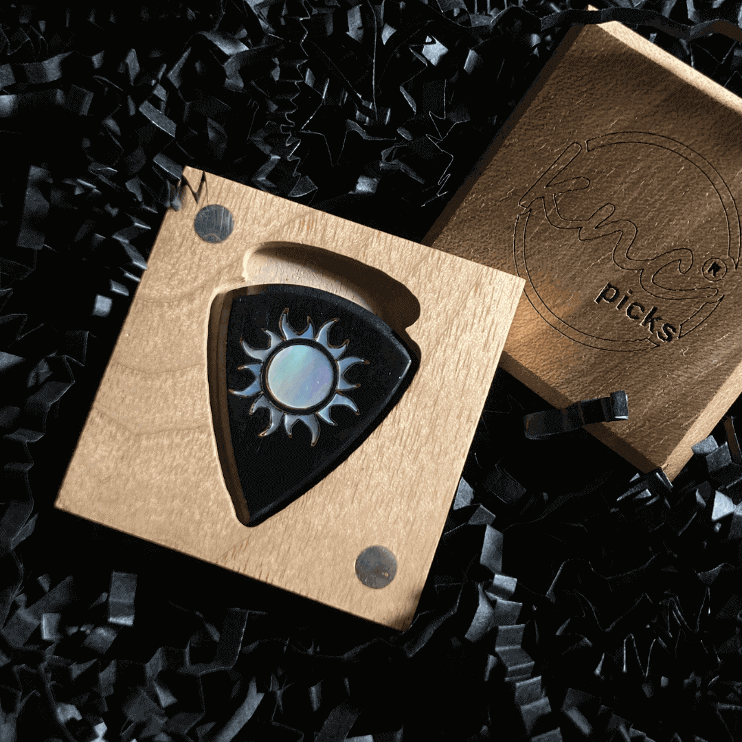 A handmade Knc Picks horn guitar pick featuring a stunning 'Burning Sun' design made from a genuine Mother of Pearl inlay.