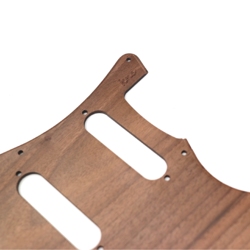 Close-up detail of the natural, dark grain of the Knc Picks walnut wood pickguard with logo on it.