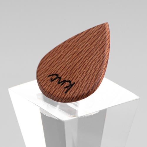 A personalized 'Lil One' Lacewood pick with a custom name laser-engraved on the small, speckled surface.