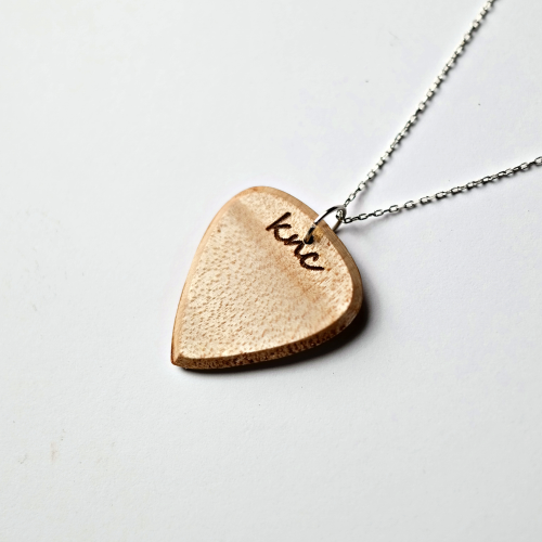 A personalized Maple pick on a necklace chain, showing a custom name laser-engraved on the light wood.
