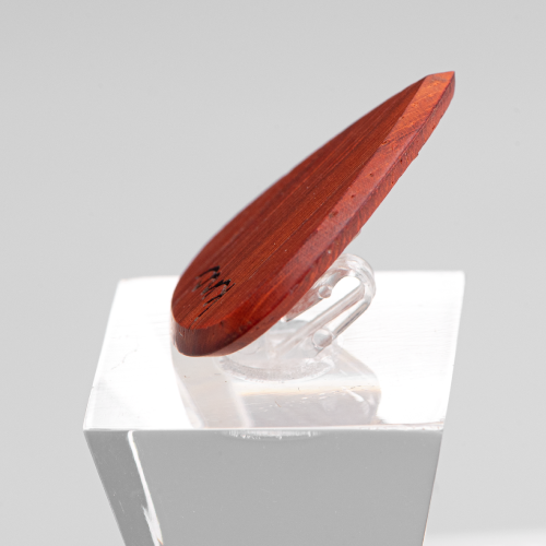 A personalized Padouk pick on a silver chain, showing a custom name laser-engraved on the vibrant red wood.