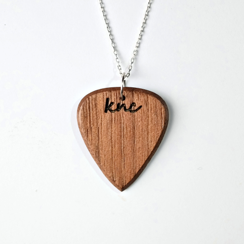 A personalized Walnut pick on a necklace, showing a custom name laser-engraved on the dark wood.