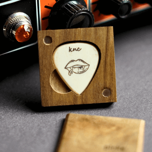 Detail of the precise laser engraving on a custom bone pick, showing a vampire logo and personalized text.