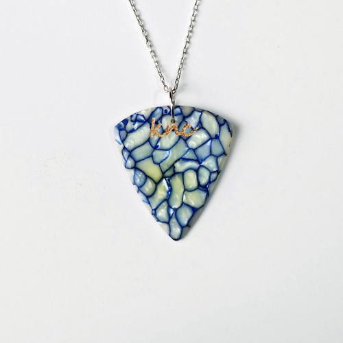 A handmade Knc Picks guitar pick made from vibrant, pearlescent Blue Galalith (Casein) material, attached to a stylish necklace chain.