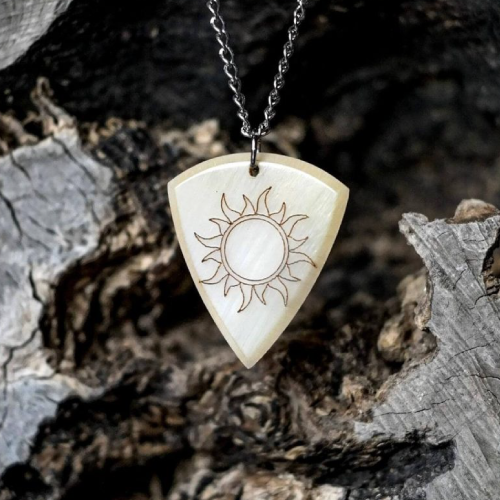 Handmade Knc Picks horn pick, engraved with a 'Burning Sun' logo, shown attached to a silver necklace chain.