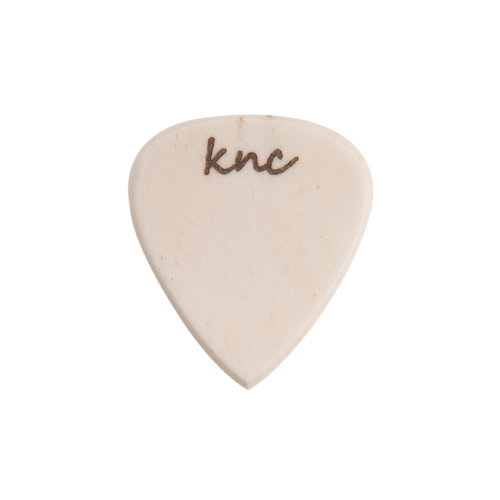 A handmade Knc Picks Custom Bone Pick, showing its natural white/off-white color and polished texture.