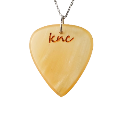 A handmade Knc Picks custom horn pick, showing its unique variegated color, attached to a silver necklace chain.