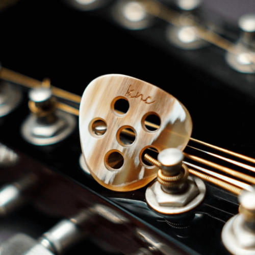 A thick (3-5mm) Knc Picks Gypsy Jazz (Manouche) pick crafted from natural, variegated horn, showing its hand-beveled edges for a loud tone.