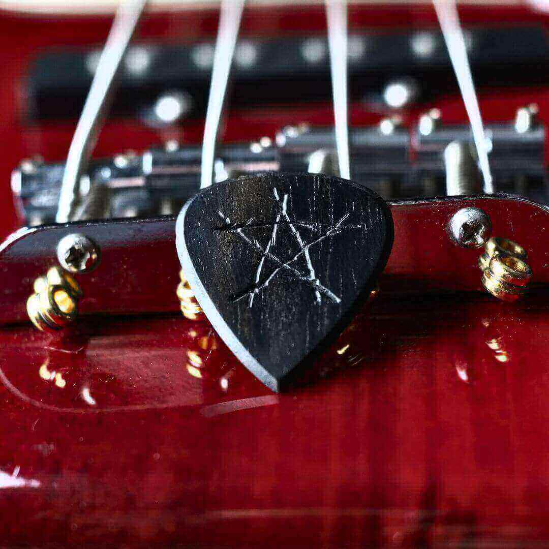 "A handmade Knc Picks Star-Shaped Ebony Pick, engraved with a Halloween theme engraved with star shaped pentagram."