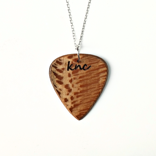 Handmade Knc Picks Sycamore (Lacewood) guitar pick, showing its unique lacy grain, attached to a stylish necklace chain.
