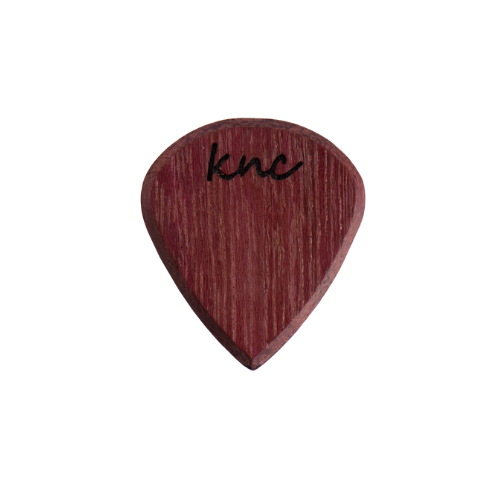 A Knc Picks handmade 'Lil One' (Jazz-style) guitar pick, crafted from vibrant natural Purpleheart wood, highlighting its small, sharp shape.