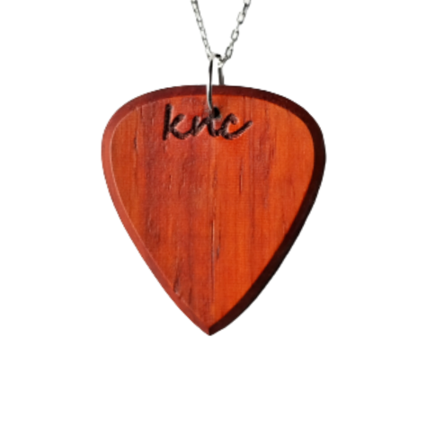 A handmade Knc Picks Padouk wood guitar pick (reddish-orange color) attached to a premium Silver necklace chain.