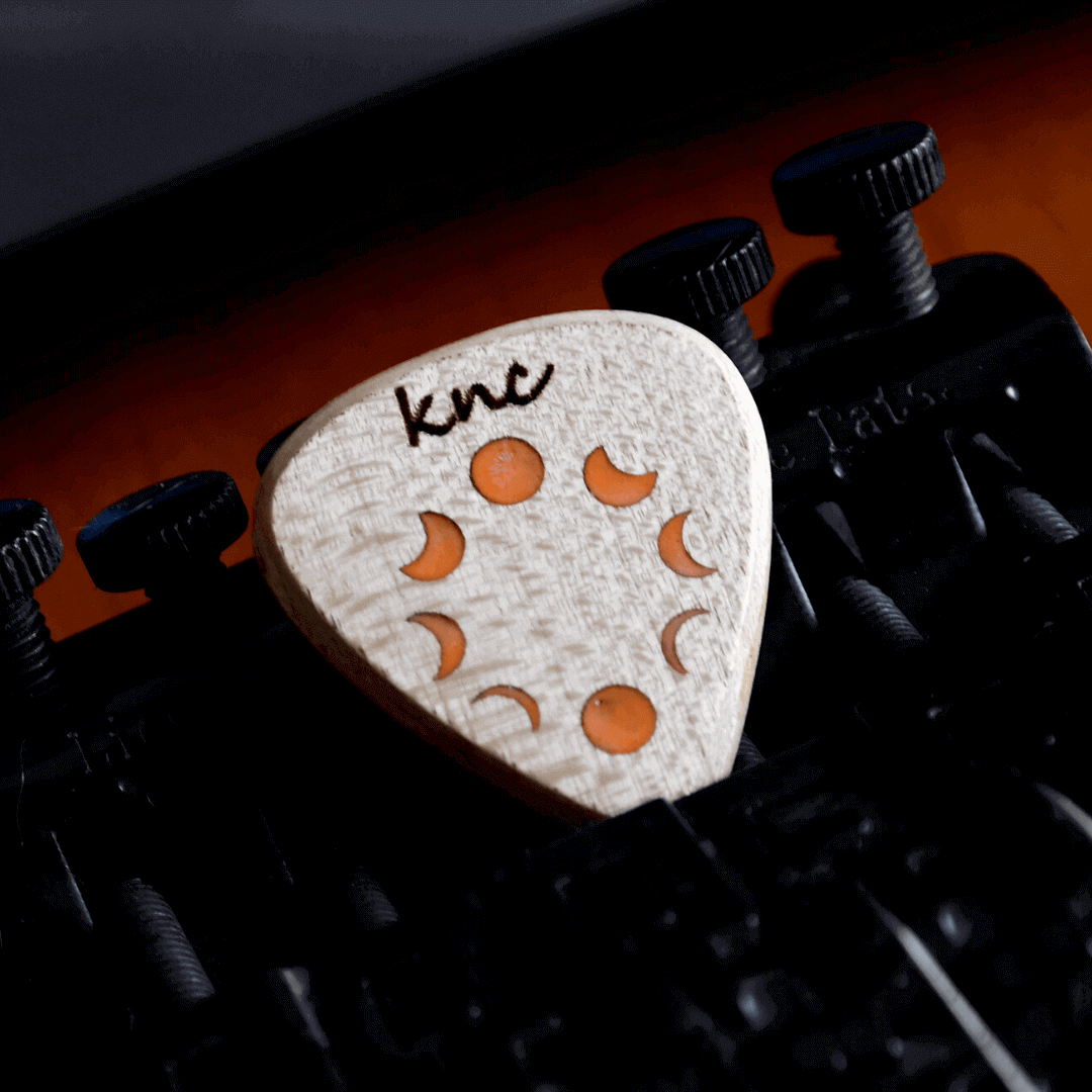 A handmade Knc Picks Maple wood guitar pick, laser-engraved with the 'Phases of the Moon' (Dolunayın Evreleri) design.