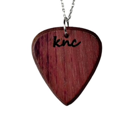 A handmade Knc Picks Purpleheart (Morkalp) wood guitar pick, showing its vibrant purple color, attached to a stylish necklace chain.