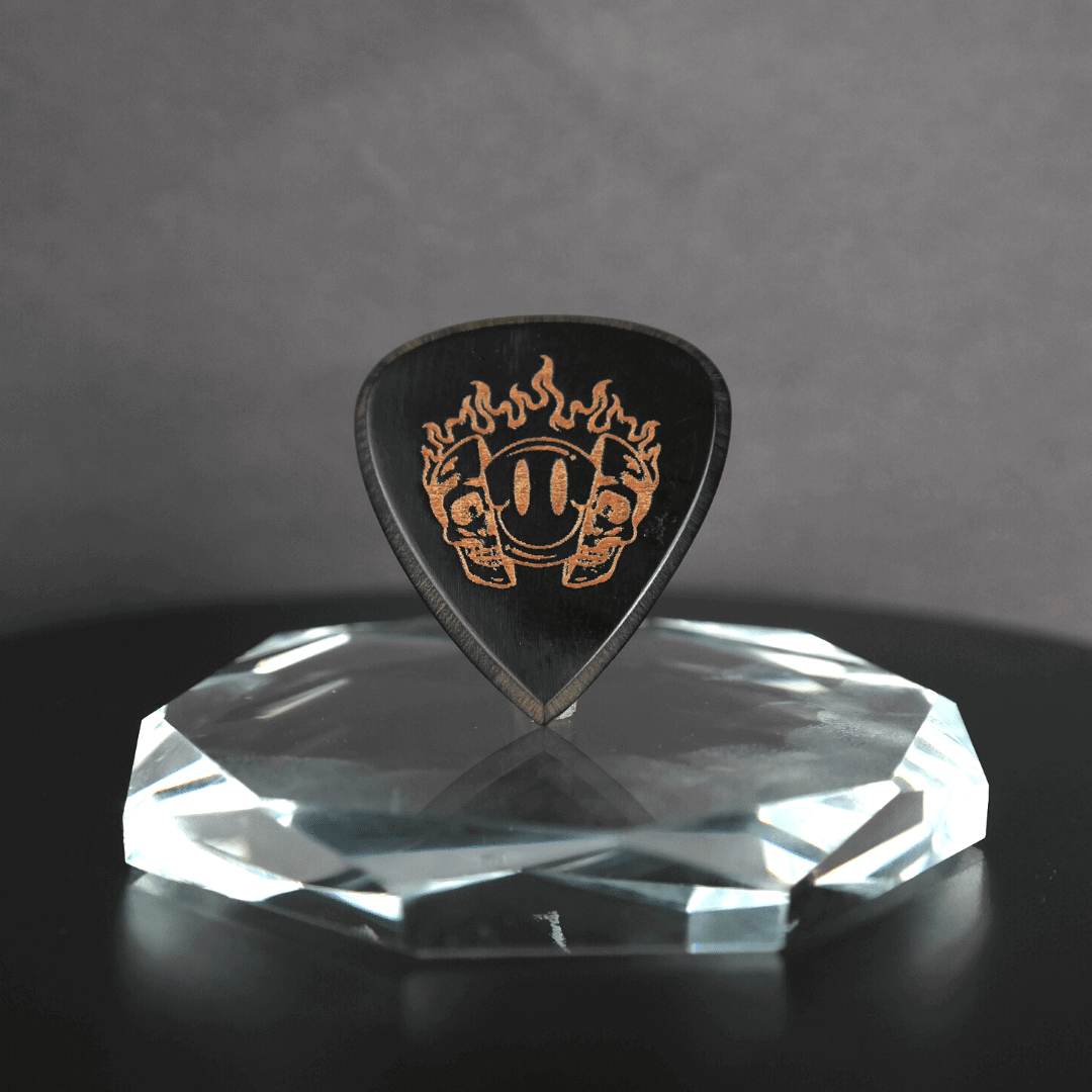 A Knc Picks handmade 2.0mm horn guitar pick featuring a unique, laser-engraved Smiling Skull design.