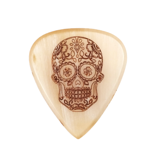 A Knc Picks handmade horn guitar pick, laser-engraved with an intricate 'Sugar Skull' (Día de Muertos) design.