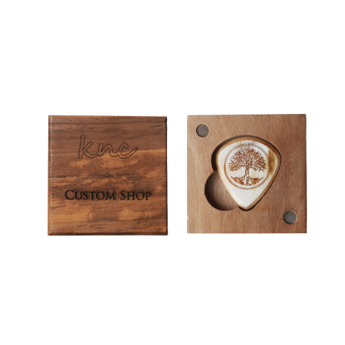 A handmade Knc Picks horn pick, laser-engraved with the 'Tree of Life' design, shown inside its included premium wooden gift box.