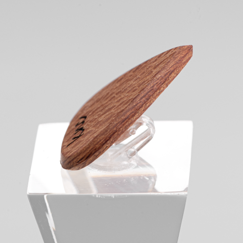 A macro close-up of the Lacewood pick, detailing the intricate, speckled grain pattern of the Sycamore wood.