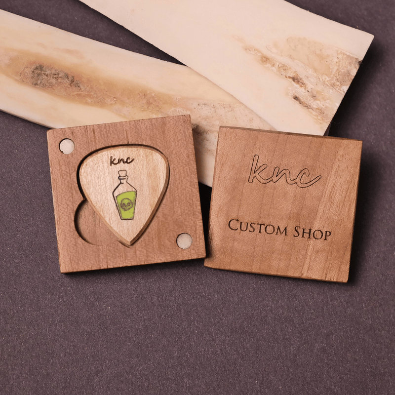 The handmade 'Poison Potion' Glowing Maple Pick by Knc Picks, shown inside its premium branded wooden gift box.