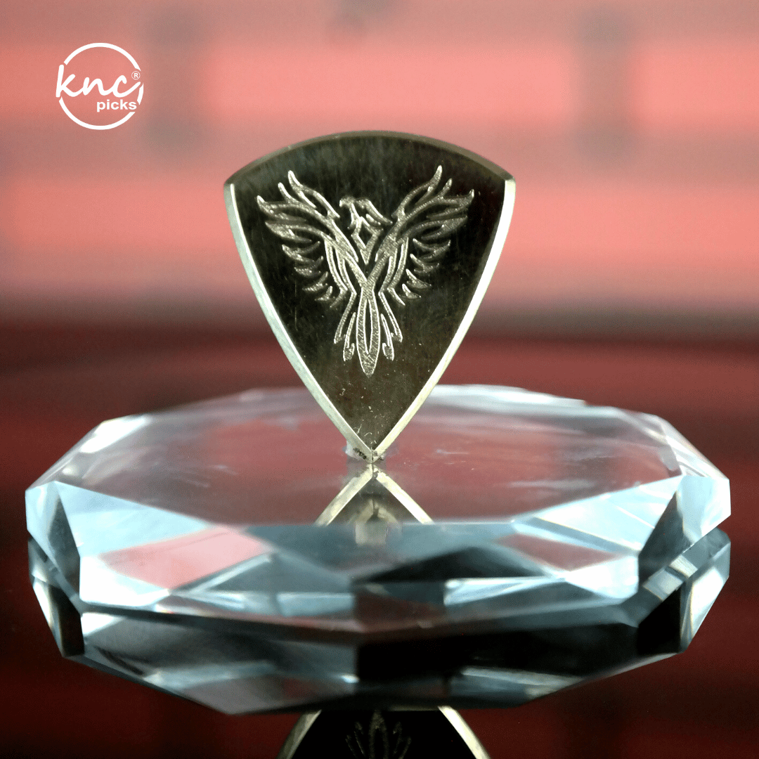 Close-up macro detail of the polished, smooth surface and beveled edge of the Knc Picks brass pick.