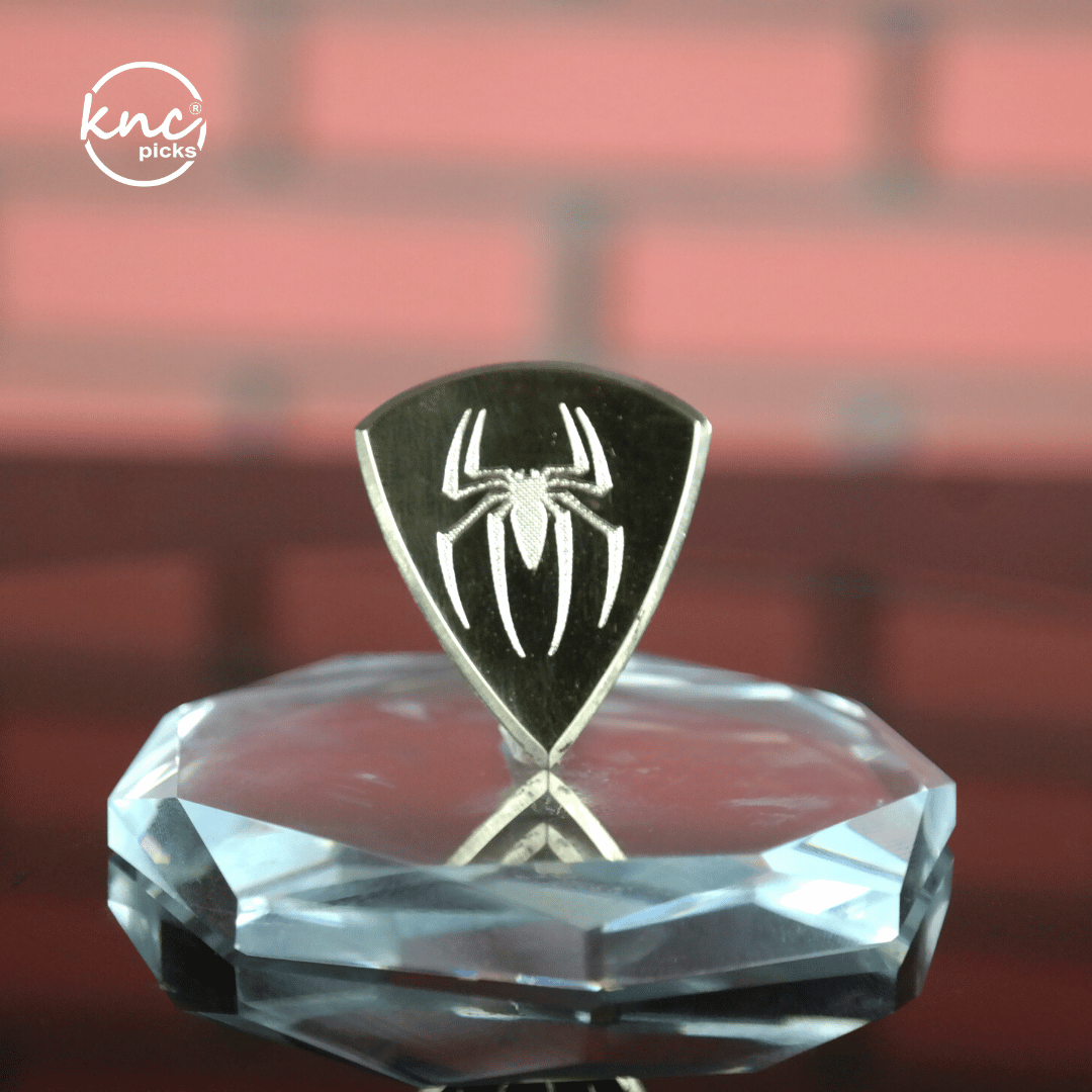 Close-up macro detail of the polished, smooth surface and beveled edge of the Knc Picks brass pick.