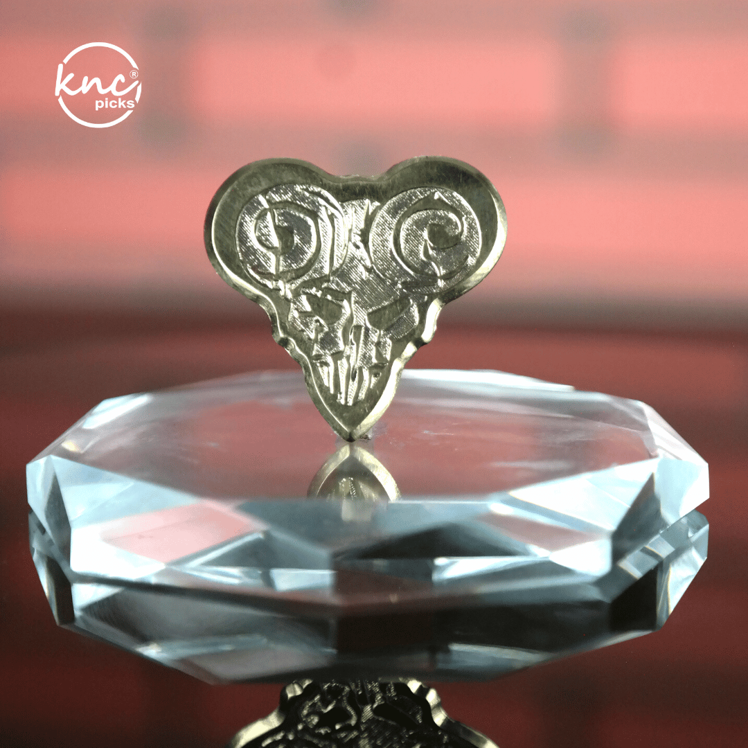 Close-up macro detail of the polished, smooth surface and beveled edge of the Knc Picks brass pick.