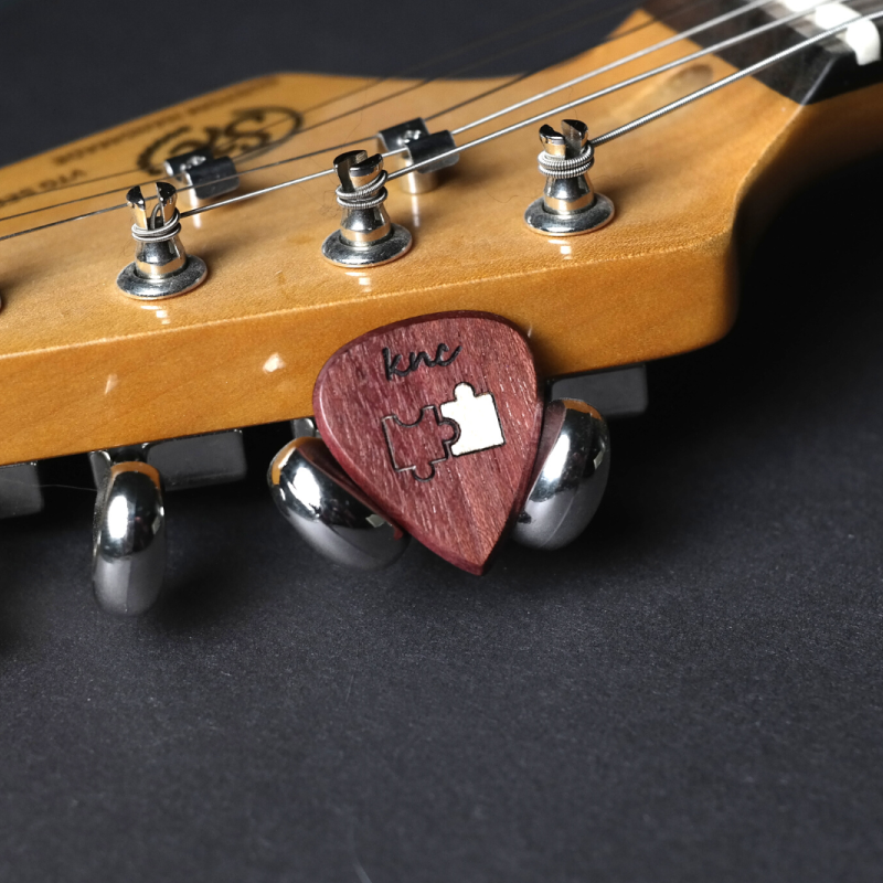 A handcrafted Purpleheart (Morkalp) wood guitar pick featuring a romantic 'Puzzle piece' design for Valentine's Day.