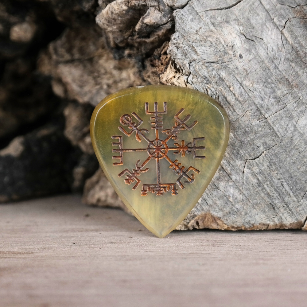A close-up macro shot showing the polished texture of the horn pick and the detail of the Vegvisir engraving.