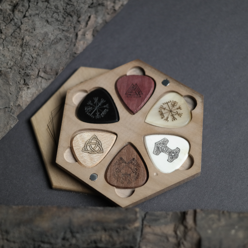 All six unique guitar picks from the Viking Saga set, showing different engraved Norse symbols on natural materials.